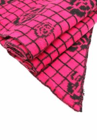 Coperta a scacchi rosa con un motivo a griglia nera, realizzata in materiale morbido, con bordo frangiato e texture arrotolata.