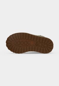 Semelle extérieure en caoutchouc marron d'une botte robuste dotée de rainures profondes et de motifs de grip en forme de croix pour une meilleure adhérence.