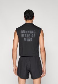 Μαύρο αμάνικο πάνω μέρος με τη φράση "RUNNING STATE OF MIND" τυπωμένη στην πλάτη, σε συνδυασμό με μαύρο σορτς. Κατασκευασμένο από ελαφρύ ύφασμα, προσφέροντας άνετη εφαρμογή.