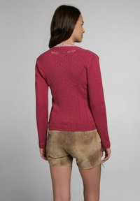 Strickpullover in Dunkelrosa mit aufwendigen Spitzenattributen am Halsausschnitt und Rücken, mit taillierter Form und geripptem Saum. Kombiniert mit braunen Wildledershorts.