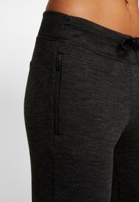 Schwarze sportliche Jogginghosen aus strukturierter Stoff, mit einem Kordelzugbund und einer verdeckten Reißverschlusstasche an der Seite.