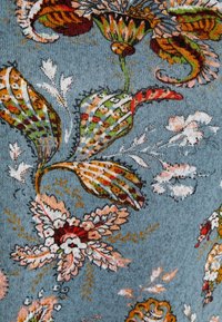 Květinový vzor látky s propracovanými vícebarevnými listy a květinovými motivy na strukturovaném světle modrém pozadí.