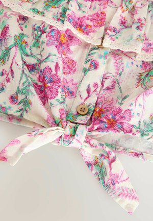 Blusa floreale con sfondo bianco, stampa floreale rosa e verde, chiusura con bottoni e dettaglio annodato sull'orlo. Tessuto texturizzato.