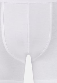 Vita bomullsboxer med ribbad textur, elastiskt midjeband och förstärkt söm längs kanterna.