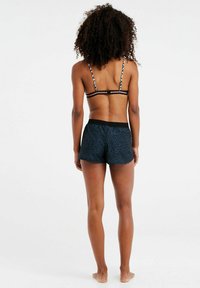 Pantaloni da bagno neri con un motivo zebroso testurizzato, vita elastica e un reggiseno abbinato con motivo e spalline sottili, arricchito da dettagli floreali.