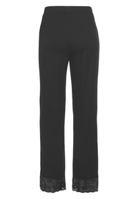 Zwarte broek van zachte stof met een elastische tailleband. Opmerkelijke kantdetails aan de zoom voegen textuur en ontwerpinteresse toe.