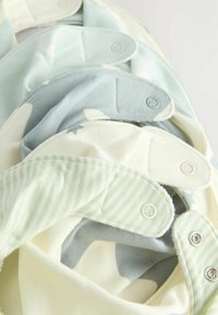 Bibs av bomullstyg i ljusa pastellfärger med tryckknappar. Mönster inkluderar ränder och stjärnor, med mjuka texturer och rundade kanter.