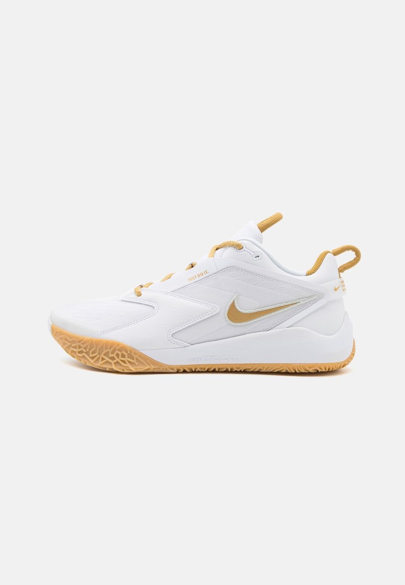 Chaussure de sport Nike blanche et dorée avec semelle en gomme, logo Swoosh latéral, col rembourré, et languettes de tirage sur la languette et le talon.