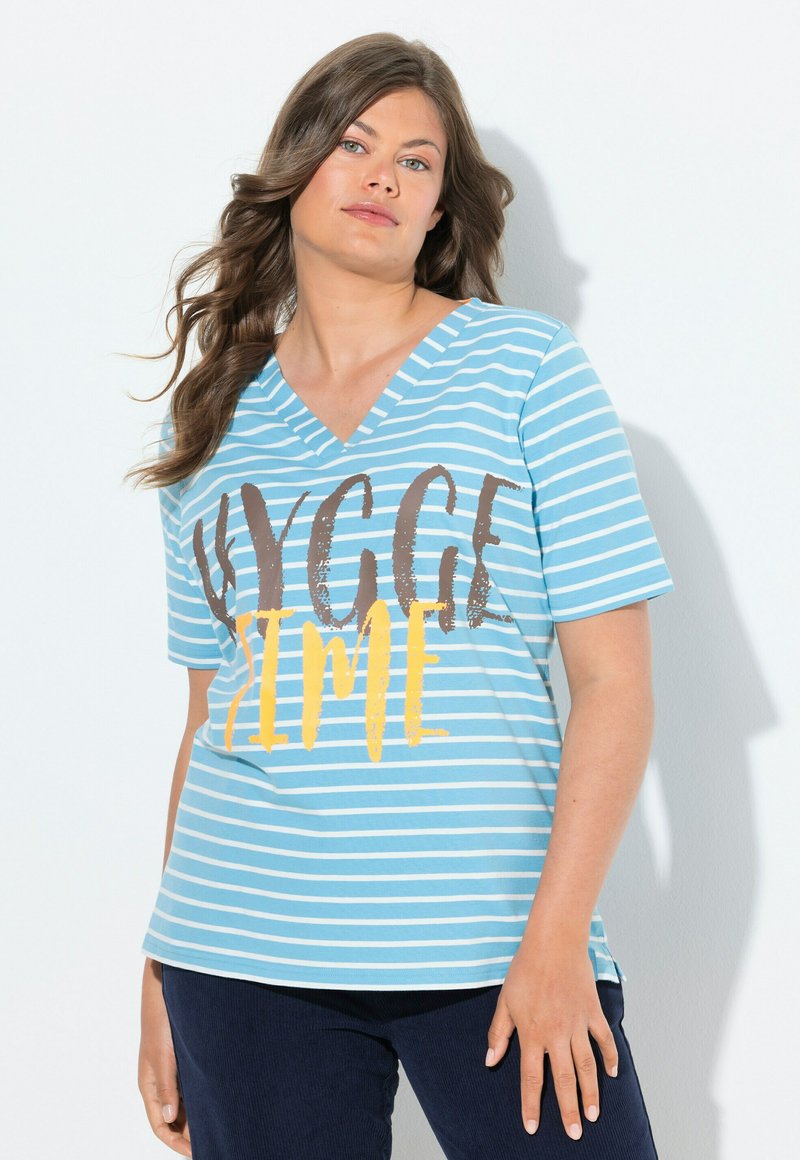 Světle modré pruhované tričko s výstřihem do V, s výrazným nápisem v hnědé a žluté barvě. Měkká tkanina, krátké rukávy a volný střih.