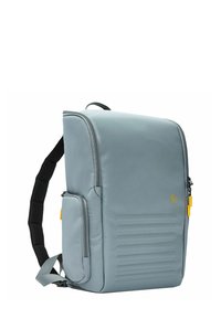 Zaino grigio con spallacci imbottiti, scomparto principale con zip, tasca laterale e sottili dettagli testurizzati sul davanti.