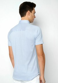 Helles blaues Kurzarm-Poloshirt mit Kragen, glatter Textur und abgerundetem Saum. Der Rücken hat eine Passe und dezente Nähte.