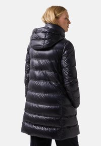 Manteau doudoune isolé navy avec capuche, présentant un design matelassé horizontal, un tissu brillant et une coupe mi-longue pour plus de chaleur.