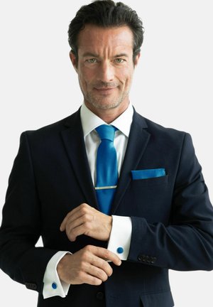 Marineblauer Anzugjacke mit weißem Hemd, türkisfarbenem Schlips und Pocket Square. Silberner Schlipsbarren und blaue Manschettenknöpfe ergänzen die weißen Manschetten.