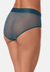 Bikini w stylu siateczkowym w kolorze morskim, z gładkim, elastycznym pasem. Posiada przezroczyste panele i kontrastujące, solidne obszycia wzdłuż krawędzi.