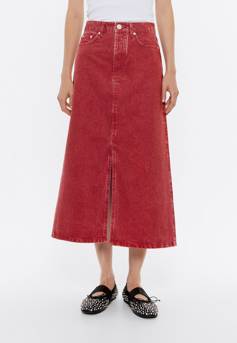 Rode denim rok met een midilange lengte, een voorovensnijding en een klassiek vijfzakkenontwerp. Voorzien van zichtbare stiksels en een knoopsluiting.