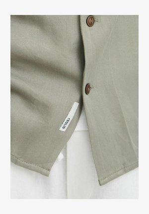 Oliivroheline nööbitav särk siledast materjalist, millel on pruunid nööbid ja valge kangalabel. Kujundatud kohandatud lõikega.