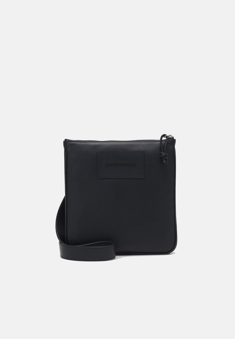 Černá kožená crossbody taška s texturovaným povrchem, obdélníkového tvaru, zipovým uzavřením a nastavitelným popruhem. Na přední straně se nachází jemné logo značky.