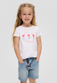 Weißes Baumwoll-T-Shirt mit drei pinken Flamingos und dem Text „Alle meine Freunde sind bunt“. Kombiniert mit Jeansshorts und einem gemusterten Taillenkordel.
