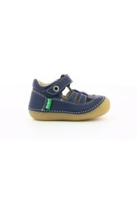 Sandal de cuero azul marino con correa ajustable, diseño recortado, costuras en contraste y suela de goma beige. Acento de logo verde en el lado.