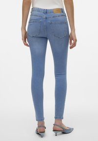 Blugi skinny de culoare albastru deschis, elastic, cu talie înaltă, dotati cu două buzunare posteriori și detalii minime de cusătură. Textură de denim neted.
