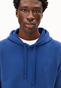 Blauer Baumwoll-Sweatshirt mit Kordelzug-Kapuze, ausgestattet mit einem kleinen, gestickten Logo auf der Brust und einer glatten Textur.