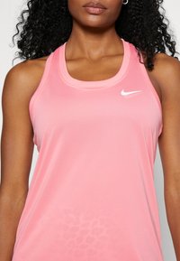 Pink Nike tank top with a scoop neckline. Features a subtle leopard print texture and a small white logo on the chest. Smooth fabric.
