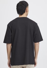 Black cotton t-shirt with short sleeves and a relaxed fit, featuring a crew neck and no visible patterns or graphics.
