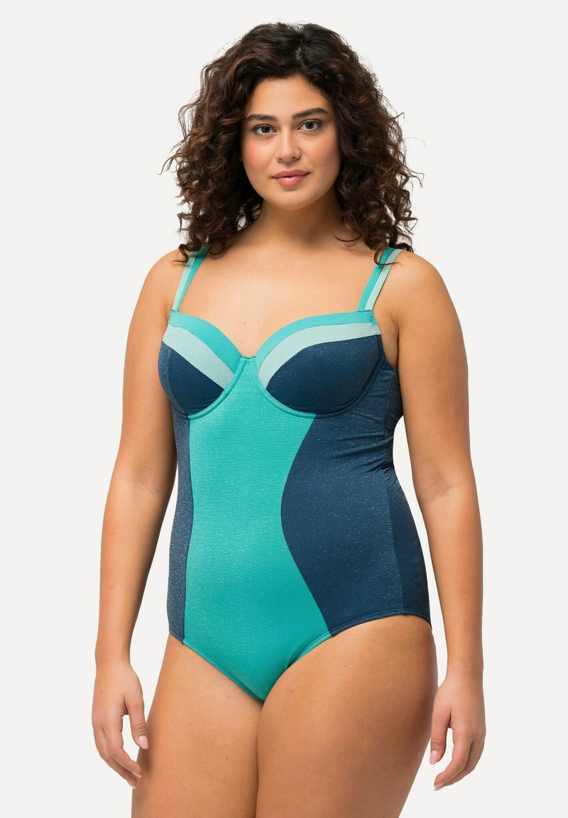 Maillot de bain avec un design structuré et des blocs de couleur bleu canard et marine. Le matériau a un léger éclat, avec des bretelles réglables et des détails de bonnets.