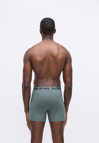 Zelene pamučne bokserice s crnim pojasom na kojem se nalazi logotip "BJÖRN BORG", prikazane sa stražnje strane. Glatka tekstura i uski dizajn.