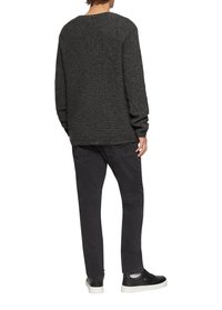 Grijze gebreide trui met lange mouwen, ronde halslijn en een ontspannen pasvorm, gecombineerd met zwarte jeans en zwarte sneakers.