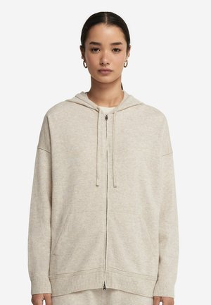 Ljus beige zip-up hoodie med dragsko i huvan, ribbade ärmslut och nederkant. Mjuk textur och två framfickor. Enkelt, utan dekorationer.