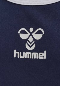 Marinblått tyg med en vit logotyp som har abstrakta former och ordet "hummel" under, tryckt med ett djärvt, modernt typsnitt.