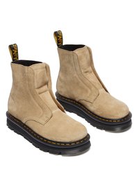 Botine din suede bej cu design slip-on, având o talpă groasă neagră cu cusături portocalii și un tab pentru a fi ușor de încălțat.