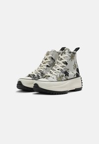 Wysokie sneakersy z roślinnym nadrukiem w kolorze szarym, czarnym i kremowym, z białymi sznurówkami, grubą podeszwą platformową oraz teksturowaną czarną gumową podeszwą.