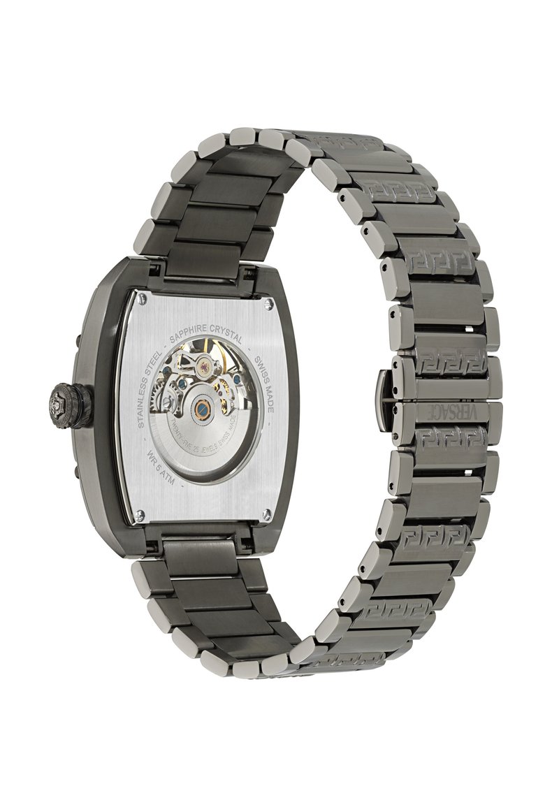 Firkantet ur i rustfrit stål med en sort børstet finish. Saphirglas bagkassen afslører urets mekanisme. Metalarmbåndet har et indgraveret mønster.