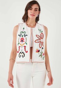 Witte geborduurde veste met kleurrijke bloempatronen, een ronde halslijn en zonder mouwen. Afgewerkt met een decoratieve rand langs de randen.