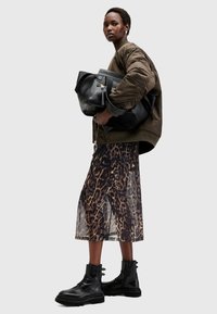 Μαύρη δερμάτινη τσάντα, σακάκι bomber σε ελαιόμορφο πράσινο, διαφανή μεσαία φούστα με λεοπάρ σχέδιο και μαύρες μποτες με κορδόνια και χοντρές σόλες.