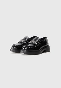 Chaussures en cuir verni noir avec une semelle épaisse, ornées de clous en argent décoratifs et d'un design à bout arrondi. Finition lisse et style minimaliste.