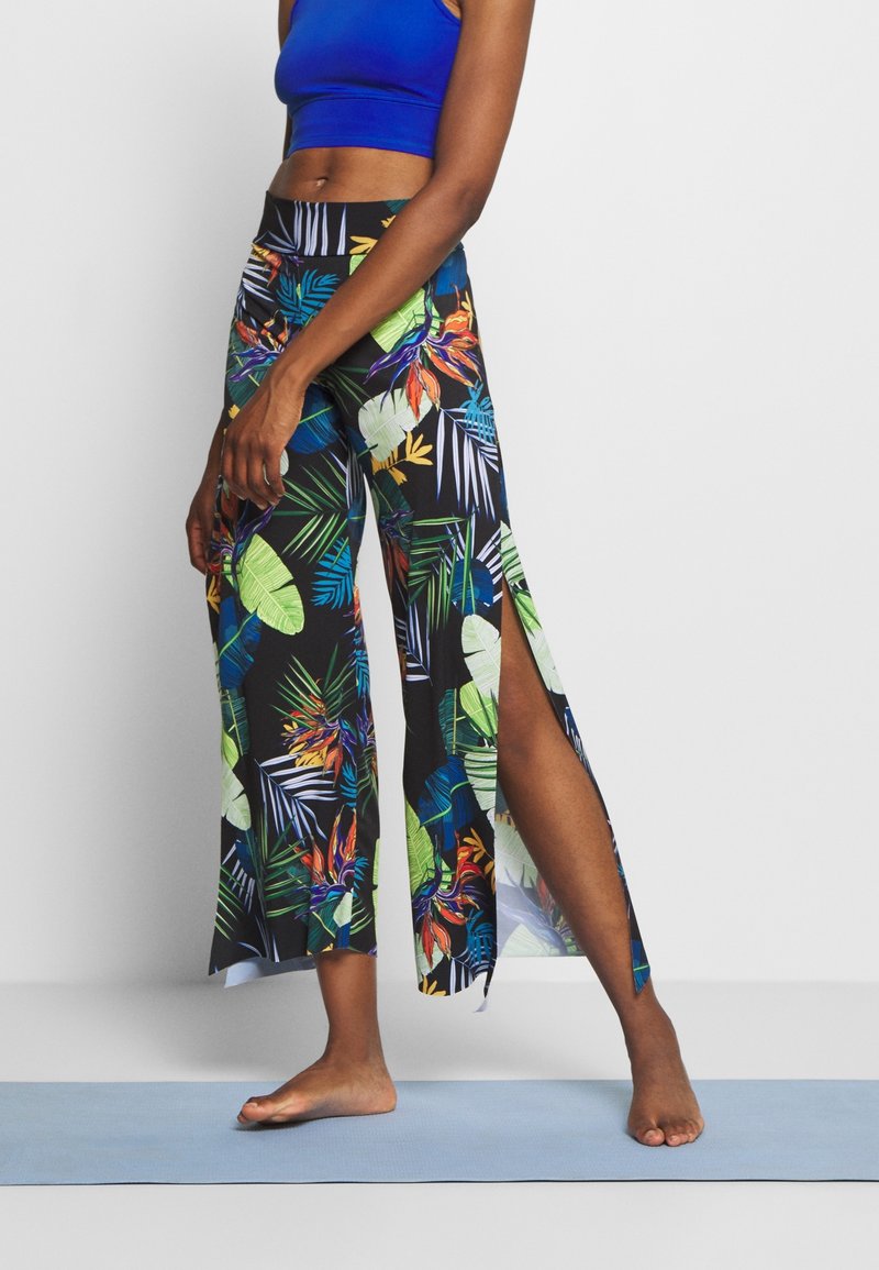 Blommönstrade, hög midja byxor med sidofickor, tillverkade av lätt tyg. Har livliga gröna, blå och gula blad mot en svart bakgrund.