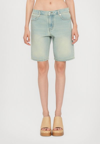 Lyseblå denimshorts med relaxet pasform, fem lommer og opsmøg. Sammen med beige platformsandaler.