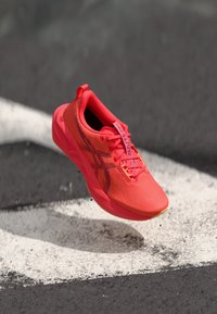 Helles pinkes Sportschuh mit einem strukturierten Mesh-Obermaterial, ausgestattet mit einem schwarzen Logo und Akzentdetails, entworfen für optimale Leistung und Agilität.