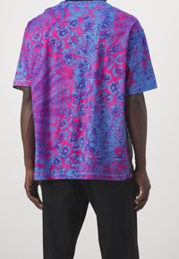 Kortärmad, oversized t-shirt i blått och rosa med ett djärvt djurtrycksmönster. Tyget ser mjukt ut med sydda fållar.