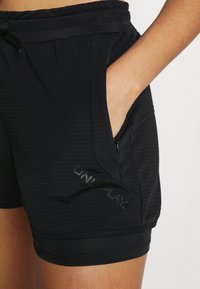 Svarta sportshorts i texturerad tyg med två sidofickor och elastisk midja med dragsko, prydda med en logotyp.