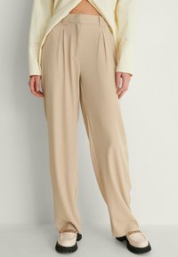 Beiga plisserade byxor med vertikala ränder, tillverkade av ett slätt material. Har hög midja och en lös, rak ben-design.