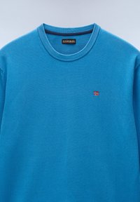 Blauwe crewneck trui van zacht fabric, met geribbelde halslijn. Klein geborduurd Noors vlaglogo op de linkerborst. Soepele textuur.