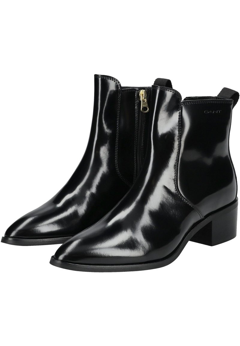 Schwarze Lackleder-Stiefeletten mit spitzer Zehenpartie, seitlichem Reißverschluss und niedrigem Blockabsatz. Sind mit dezentem Branding an der Seite versehen.