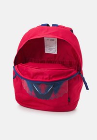 Czerwony plecak z motywem Marvela, z logo Spider-Mana, niebieskim zamkiem błyskawicznym, otwartą główną komorą oraz wewnętrzną etykietą informującą o użyciu materiałów ekologicznych.