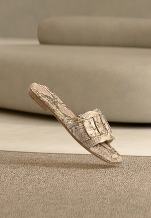 Slangeskinnmønstret sandall med flat såle, med bred stropp og teksturert overflate. Fargene er beige og brun, med subtile mønstre.