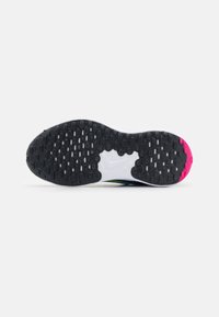 Suela de zapatilla Nike con una superficie de goma negra texturizada, media suela blanca y acentos en rosa. Presenta patrones de tracción ovalados para mayor agarre.