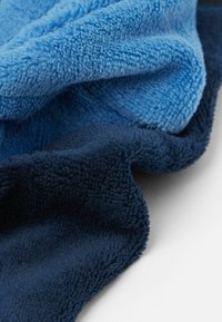 Soft fleece blanket in light blue and dark navy. Textured fabric with a plush, thick feel. Smooth finish with no visible patterns or hardware.